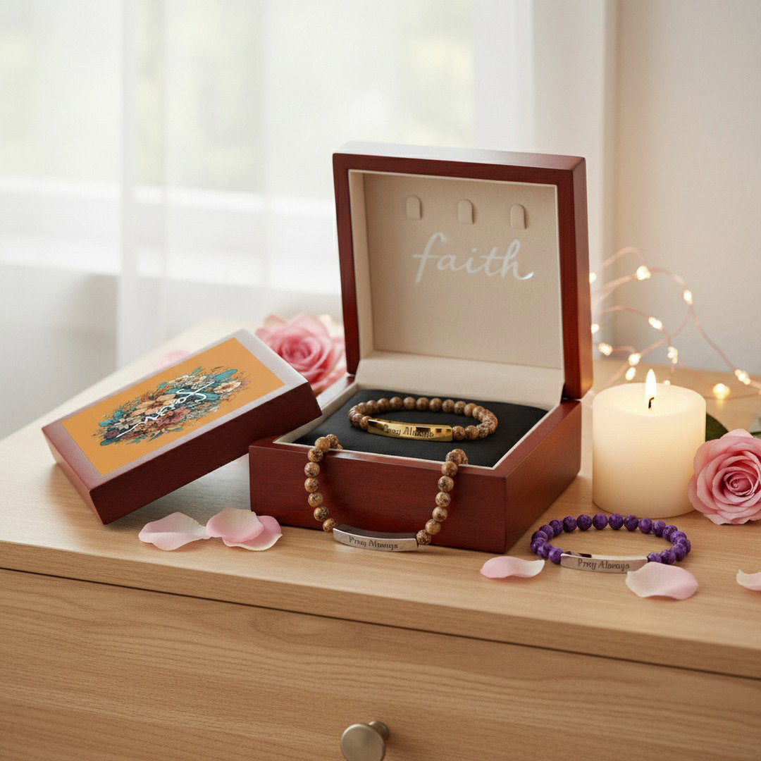 Mahogany Faith floral cross keepsake jewelry box open with Pray Always beaded bracelet inside displayed on light wood dresser with white pillar candle, pink roses, rose petals, and warm fairy lights, cozy faith gift lifestyle photo