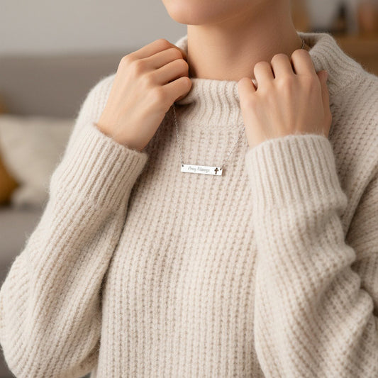 Silver Pray Always engraved bar necklace worn by woman in cozy cream sweater, faith jewelry gift for her