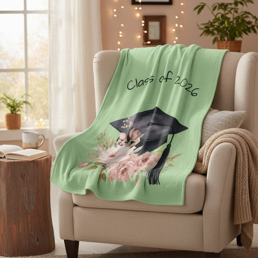 Class of 2026 green velveteen graduation blanket on cozy armchair with warm fairy lights, meaningful gift for her