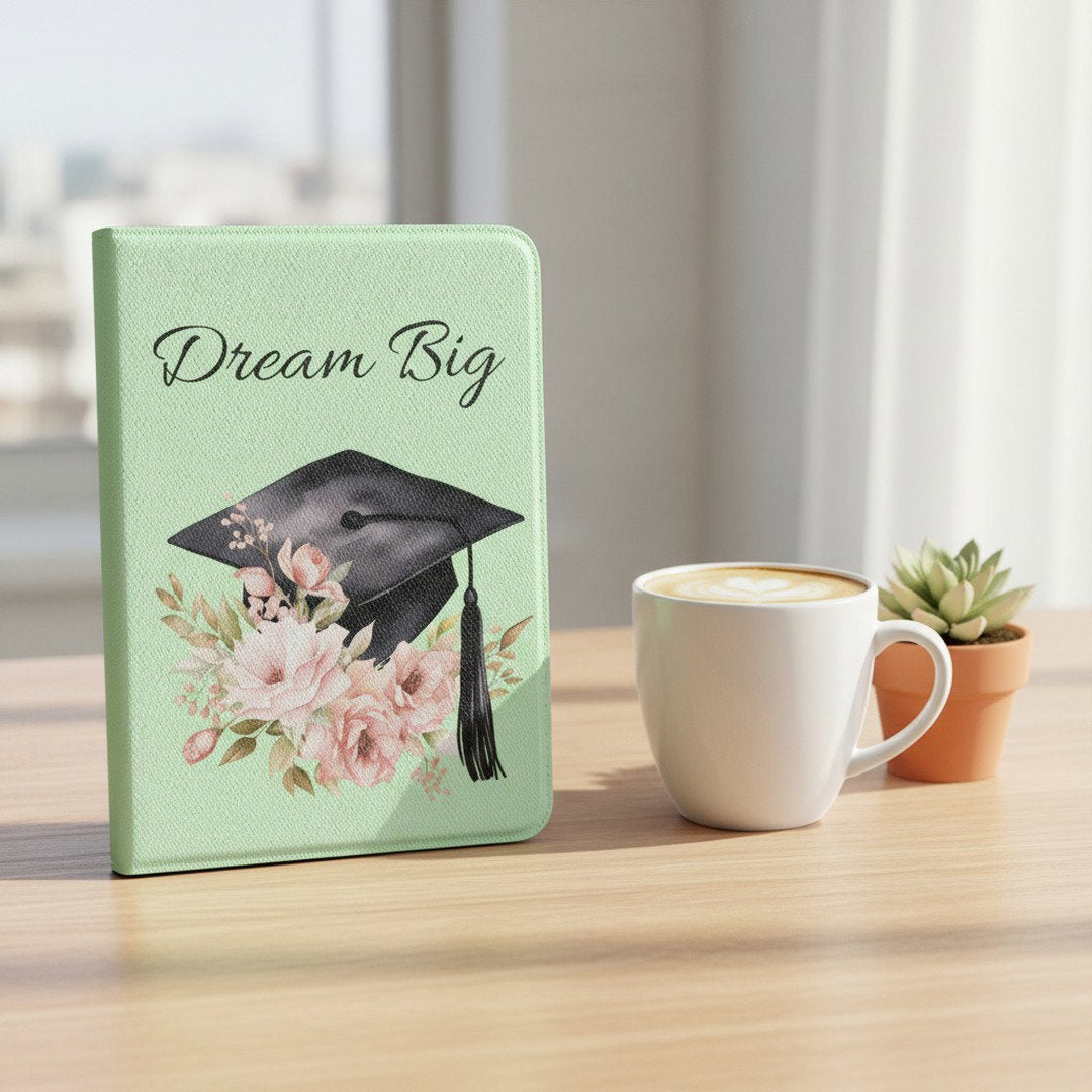 Dream Big floral graduation Kindle case on light wood desk beside white latte mug and small succulent, feminine college student gift