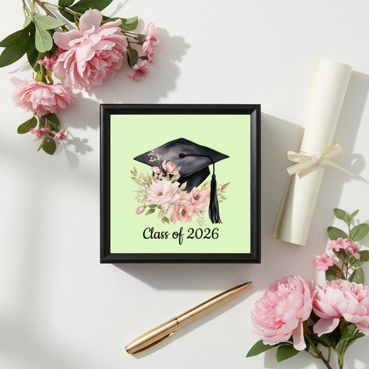 Class of 2026 floral graduation jewelry box flat lay with pink roses, diploma scroll, and gold pen on white background