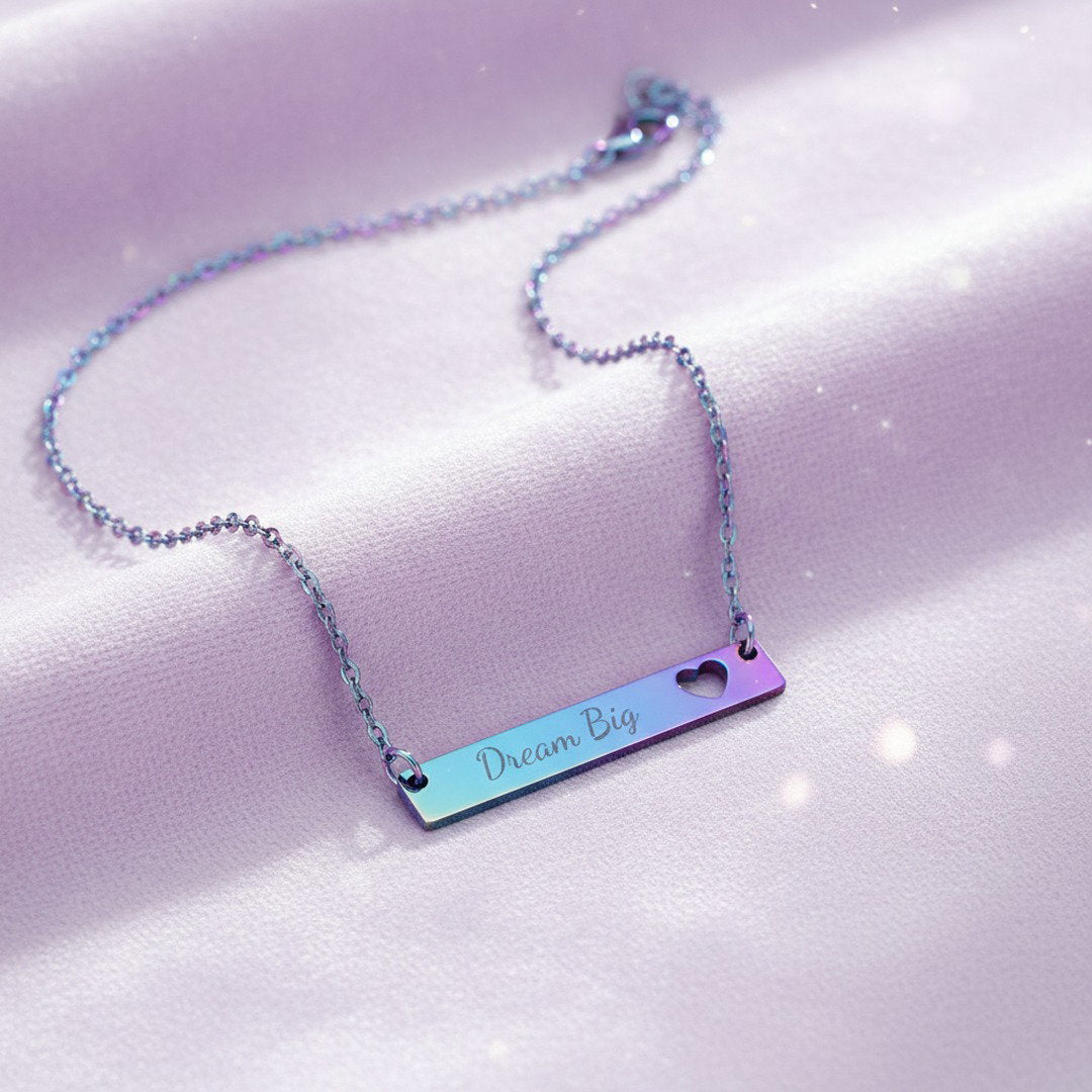 Rainbow iridescent Dream Big bar necklace with heart cutout on soft lavender satin with glitter bokeh background