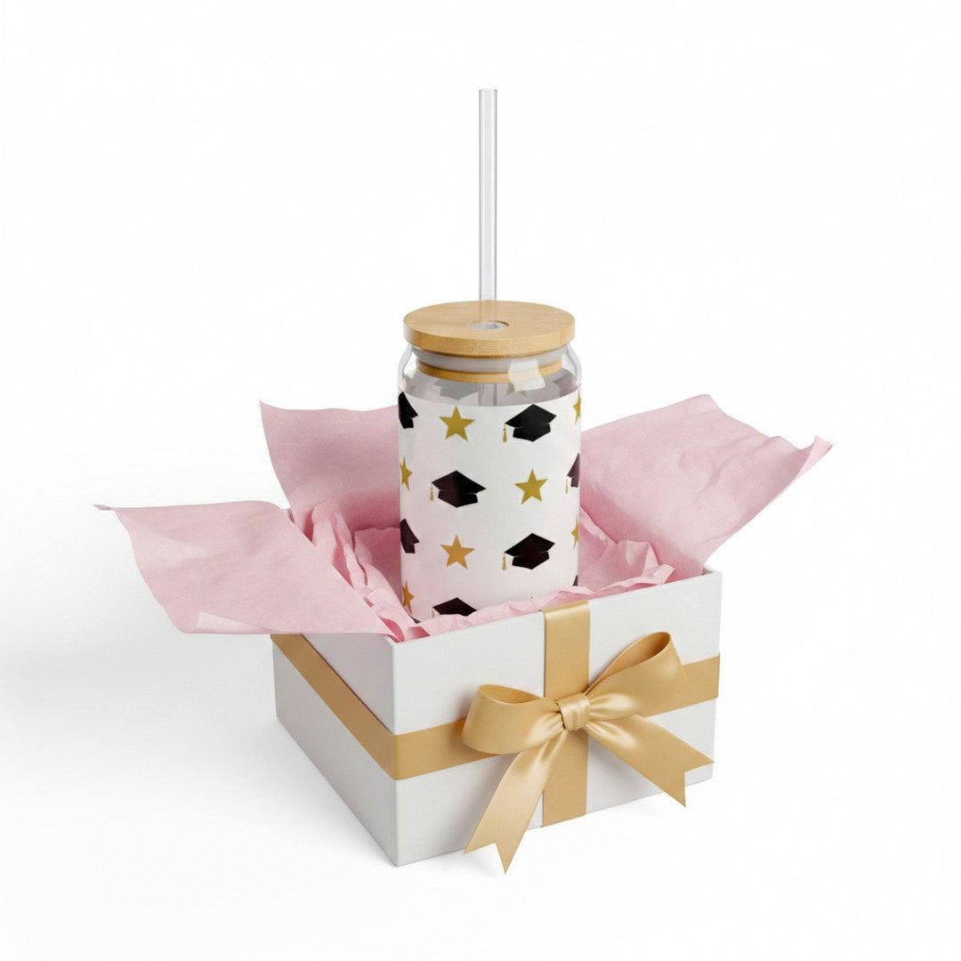 Graduation sipper glass with black grad caps and gold stars pattern in open white gift box with pink tissue paper and gold satin bow, Class of 2026 graduation gift presentation