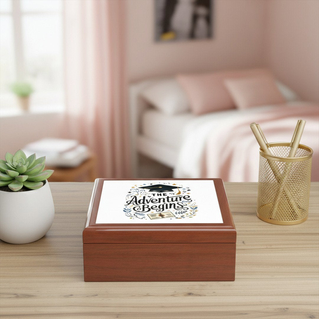 The Adventure Begins graduation keepsake jewelry box on a desk with a succulent and gold pen holder in a blush bedroom setting