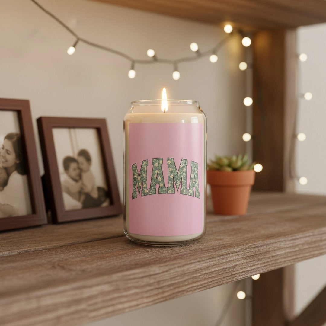 MAMA soy candle in glass jar with pink label on wooden shelf, framed family photos and succulent nearby, warm string lights glowing in background