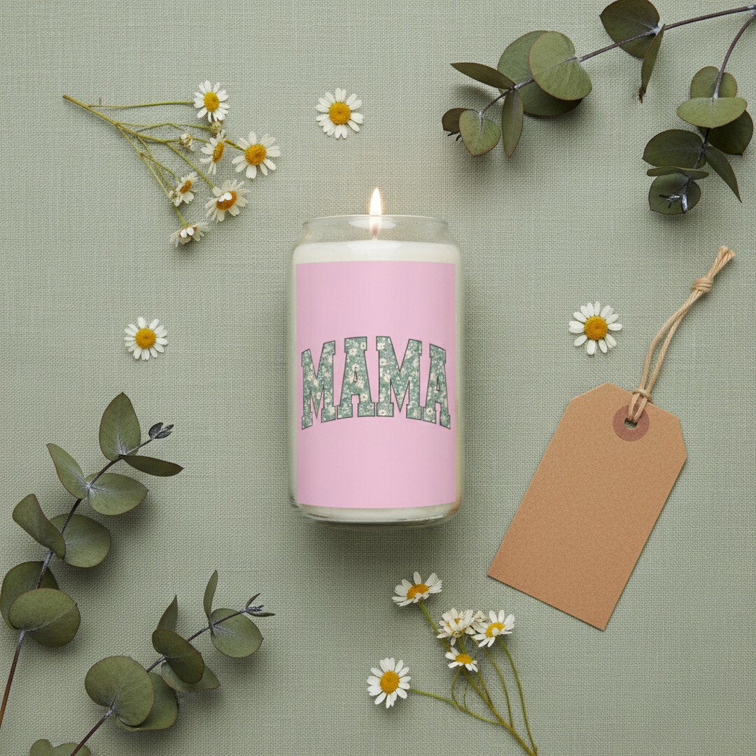 Flat lay of MAMA soy candle in glass jar on sage green linen background with white daisies, eucalyptus sprigs, and kraft gift tag, thoughtful mom gift