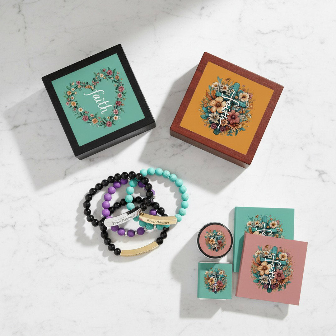 Black and mahogany Faith keepsake jewelry boxes with floral cross and faith wreath lid designs displayed with black, purple, and turquoise Pray Always beaded bracelets on white marble surface, faith gift bundle color options flat lay