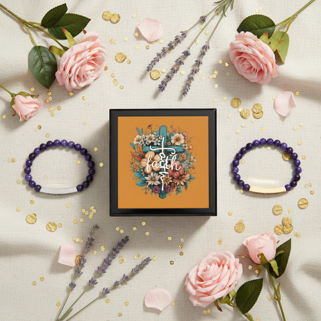 Black Faith floral cross keepsake jewelry box surrounded by two purple Pray Always beaded bracelets, pink roses, lavender sprigs, and gold confetti on cream linen fabric, faith gift bundle hero flat lay