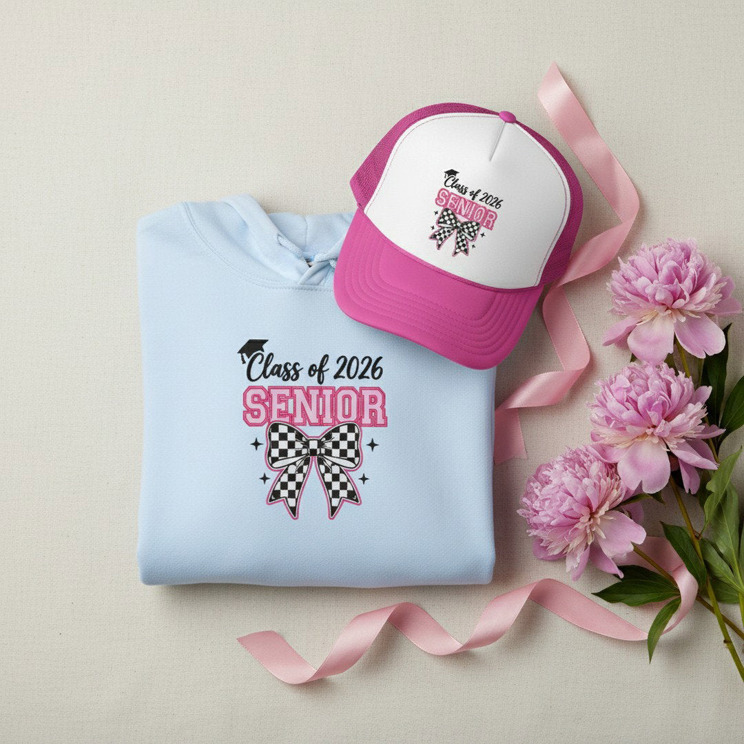 Light blue Class of 2026 Senior checkered bow hoodie folded flat with pink and white Senior trucker cap, pink satin ribbon, and fresh pink peonies on cream linen background, graduation hoodie and hat bundle gift